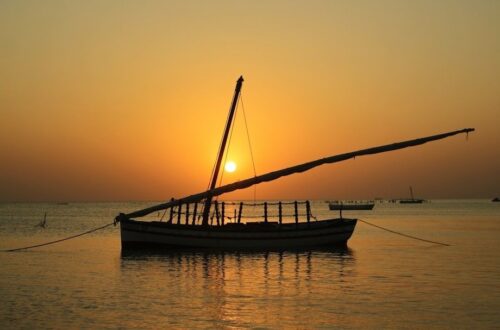 Traditionele houten dhow bij zonsondergang op kalm zeewater