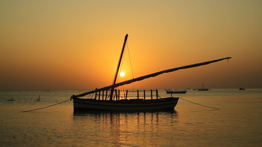 Traditionele houten dhow bij zonsondergang op kalm zeewater