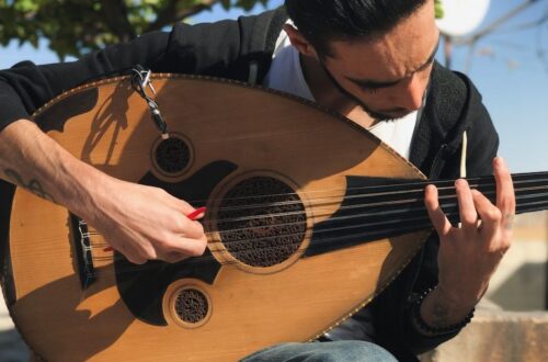 Muzikant bespeelt een oed met een rode plectrum in de buitenlucht