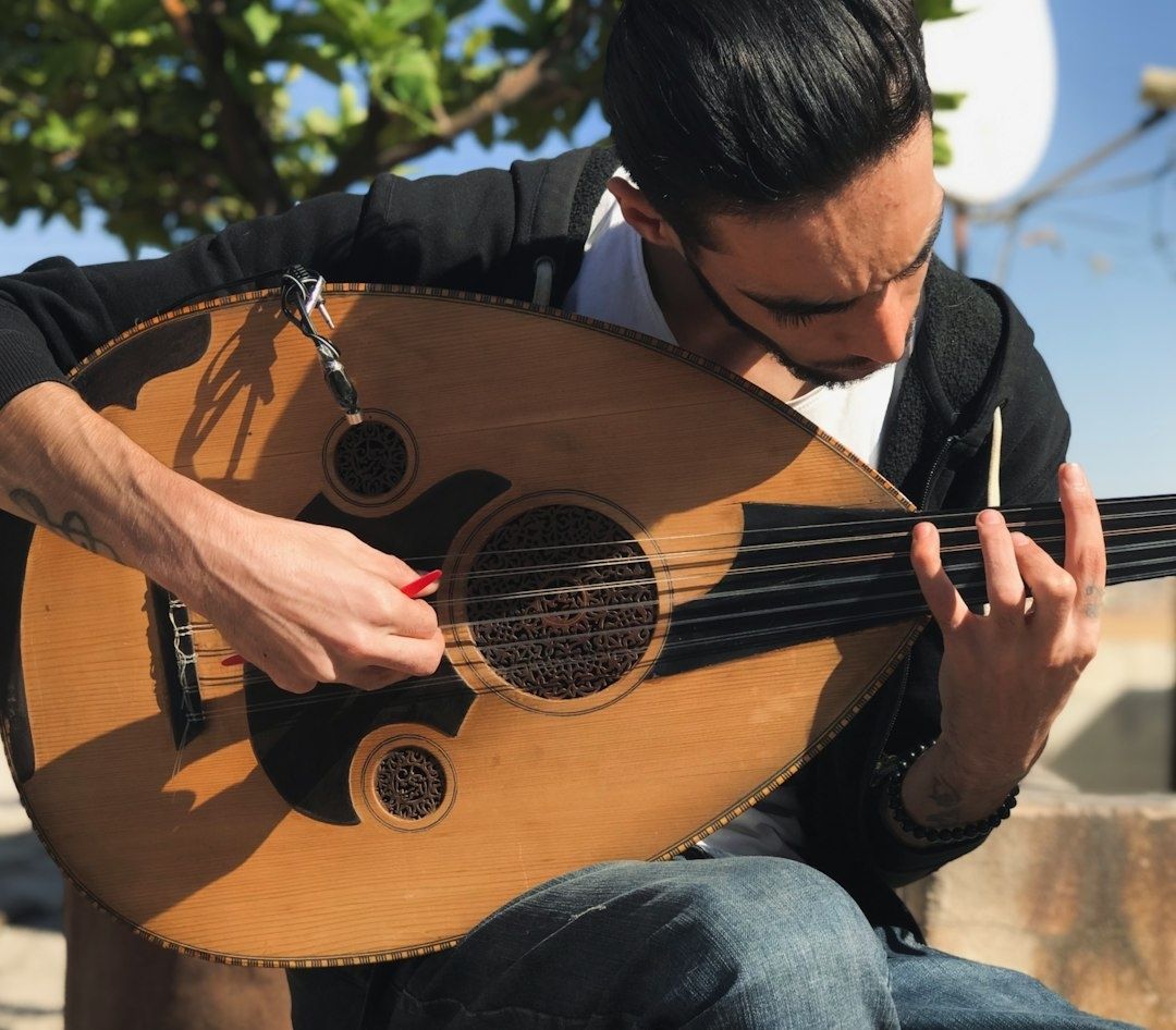 Muzikant bespeelt een oed met een rode plectrum in de buitenlucht