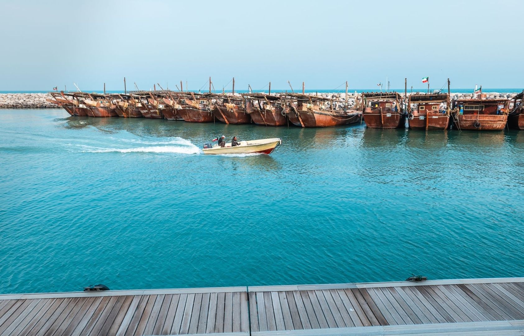 Traditionele houten dhows liggen aangemeerd aan een turquoise kust